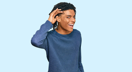 Young african american man wearing casual winter sweater smiling with hand over ear listening an hearing to rumor or gossip. deafness concept.