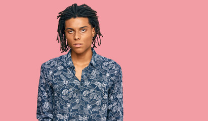 Young african american man wearing 80s shirt with serious expression on face. simple and natural looking at the camera.