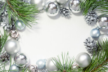 Light Christmas background with silver balls, cones and pine branches on a white background. New Year celebration.