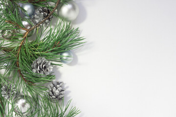 Fototapeta na wymiar Light Christmas background with silver balls, cones and pine branches on a white background. New Year celebration.
