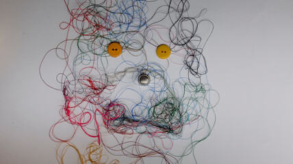 Tangle of sewing thread in various colors in the shape of a dog on a white background, simulating...