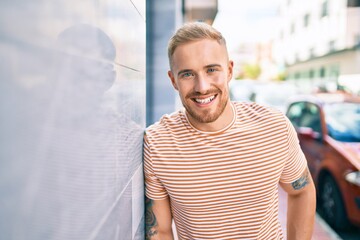 Young irish man smiling happy leaning on the wall at street of city.