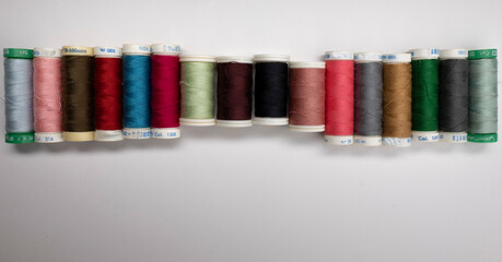 Rolls of thread for sewing of various colors and sizes, white, black, blue, pink, green on, white...