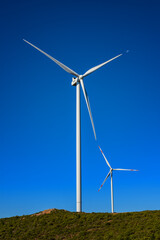 Wind turbines on a beautiful blue sky in a mountain wind farm in Sardinia. Renewable energy concept, green energy generation. Energy industry.