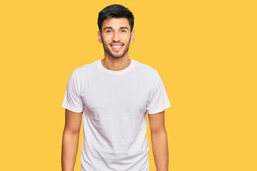 Young handsome man wearing casual white tshirt with a happy and cool smile on face. lucky person.