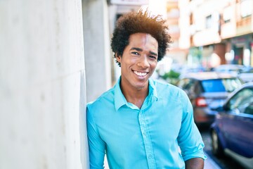 Young handsome african american man wearing casual clothes smiling happy. Leaning on the wall with smile on face at town street.