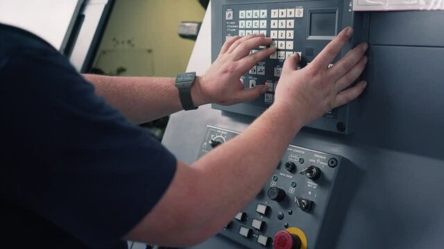 Young worker programming lathe machine in factory