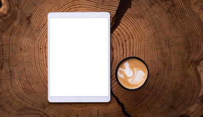 Obraz na płótnie Canvas A white tablet with an empty screen and a Cup of coffee on a wooden table.