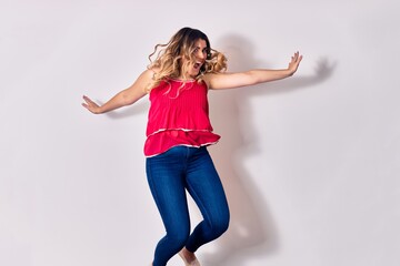 Young beautiful caucasian woman wearing casual clothes smiling happy. Jumping with smile on face and arms opened over isolated white background