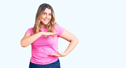 Young caucasian woman wearing sportswear gesturing with hands showing big and large size sign, measure symbol. smiling looking at the camera. measuring concept.