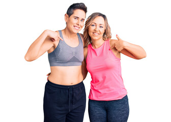 Fototapeta na wymiar Couple of women wearing sportswear looking confident with smile on face, pointing oneself with fingers proud and happy.