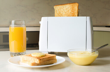 European breakfast in the kitchen in the morning. White electric bread toaster with orange juice with toasts and jam
