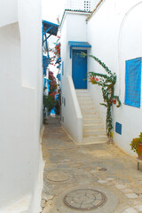 A narrow street in Mediterranean architectural style with blue and white windows and doors. Tunisia