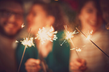 Group of friends with sparklers celebrating Christmas at home