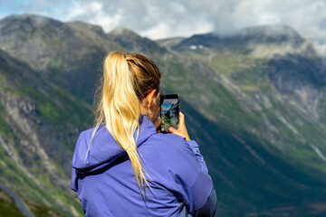 Urlaub in Süd-Norwegen: Frau macht ein Handy Foto am Vistor Center Trollstigen - Besucher /...