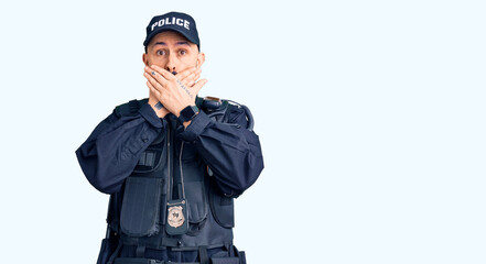 Young handsome man wearing police uniform shocked covering mouth with hands for mistake. secret concept.