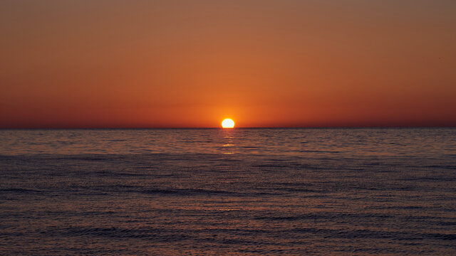 Beautiful red pink orange dawn on the sea without waves © di_ryan