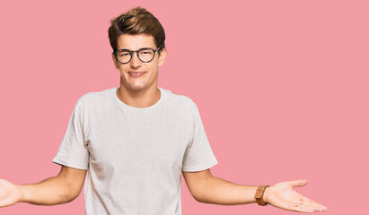 Handsome caucasian man wearing casual clothes and glasses clueless and confused with open arms, no...