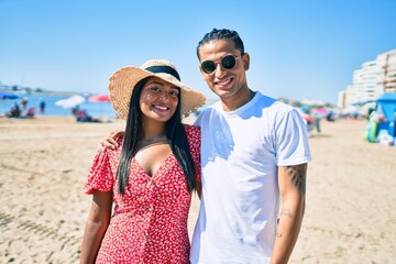 Young latin couple smiling happy and hugging at the beach.