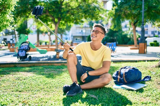 Young hispanic student smiling happy making selfie by the smartphone sitting at the university campus
