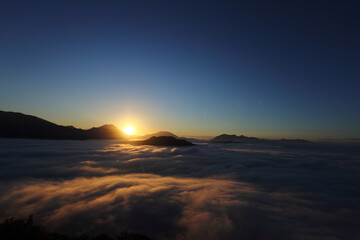 new day - the sun at dawn with fog and backlit mountains