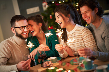Group of friends holding sparklers celebrating Christmas at home
