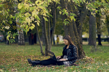 young woman works for a laptop in the park. the student is preparing for exams