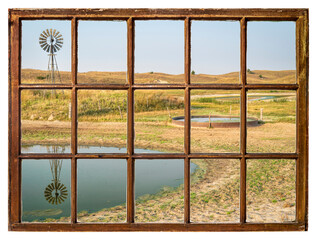 cattle drinking hole in a prairie of Nebraska Sandhills - fall morning scenery as seen from a vintage sash window