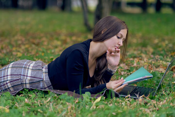 young woman works for a laptop in the park. the student is preparing for exams