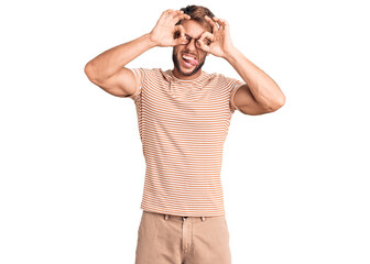 Fototapeta premium Young caucasian man wearing casual clothes and glasses doing ok gesture like binoculars sticking tongue out, eyes looking through fingers. crazy expression.