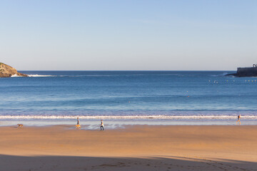 San Sebastian, Spain - 10/11/2019: Seashore with unknown people. Wide aerial beach in morning sunlight. People walking on coast of Biscayne bay. Healthy and relax lifestyle. Scenic seascape in morning
