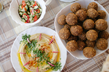 A table spread of middle-eastern dishes like hummus and falafel and salad