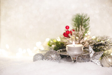 Christmas decoration with candles, fir branch and balls on snow