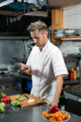 Contemporary young professional chef looking through list of ingredients