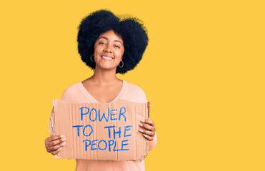 Young african american girl holding power to the people banner looking positive and happy standing and smiling with a confident smile showing teeth