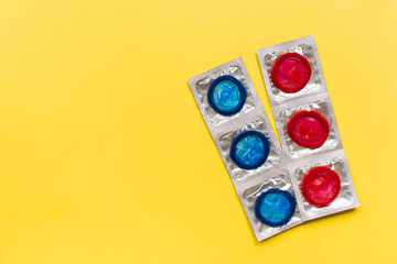 Composition with colorful condoms on yellow background. Safe sex and contraceptive concept. Flat lay, top view, copy space.