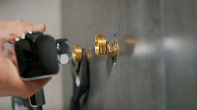Male hand with a wrench to wind the Cam to install a shower faucet.