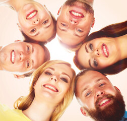 Happy, smiling friends standing together and looking at camera over orange background.