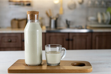 milk bottle and a glass on the kitchen table. Milk on a wooden board indoors.Organic farmer's Breakfast