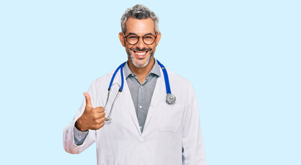 Middle age grey-haired man wearing doctor uniform and stethoscope smiling happy and positive, thumb...