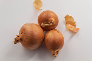 On a white background lie three ripe bulbs with husk