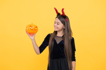 look what i have. cheerful kid hold creepy pumpkin. carnival costume party. trick or treat. celebrate the holidays. jack o lantern. halloween devil girl. happy childhood. teenage child in imp horns