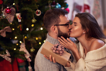 Adult couple with present over Christmas tree