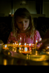 little child playing with christmas traditional custome nut shell with burning candle floating on water