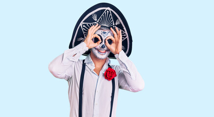 Man wearing day of the dead costume over background doing ok gesture like binoculars sticking tongue out, eyes looking through fingers. crazy expression.