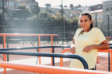 Pleasant strong female relaxing after workout at stadium