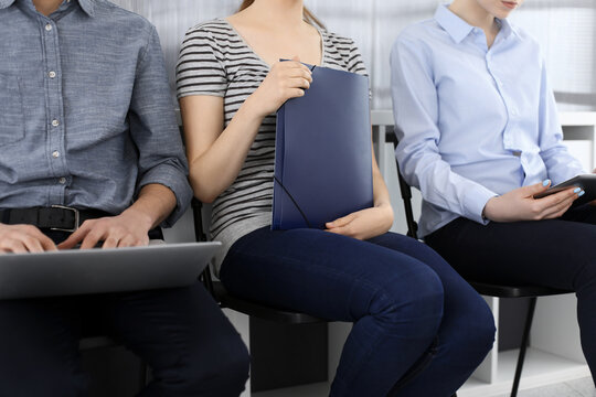 Group Of Casual Dressed Business People Sitting In A Line While Waiting For A Job Interview. Unemployment As The Effects Of The COVID Crisis