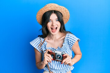 Young beautiful caucasian girl holding vintage camera celebrating crazy and amazed for success with open eyes screaming excited.