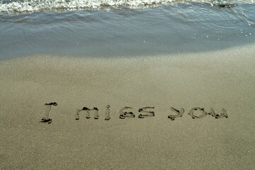 Phrase I Miss You written on beach sand