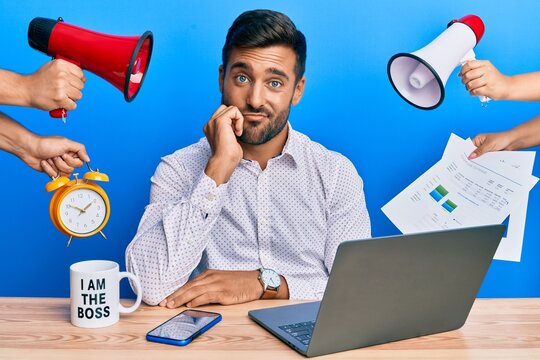 Handsome hispanic man working at the office being stressed out thinking looking tired and bored with depression problems with crossed arms.